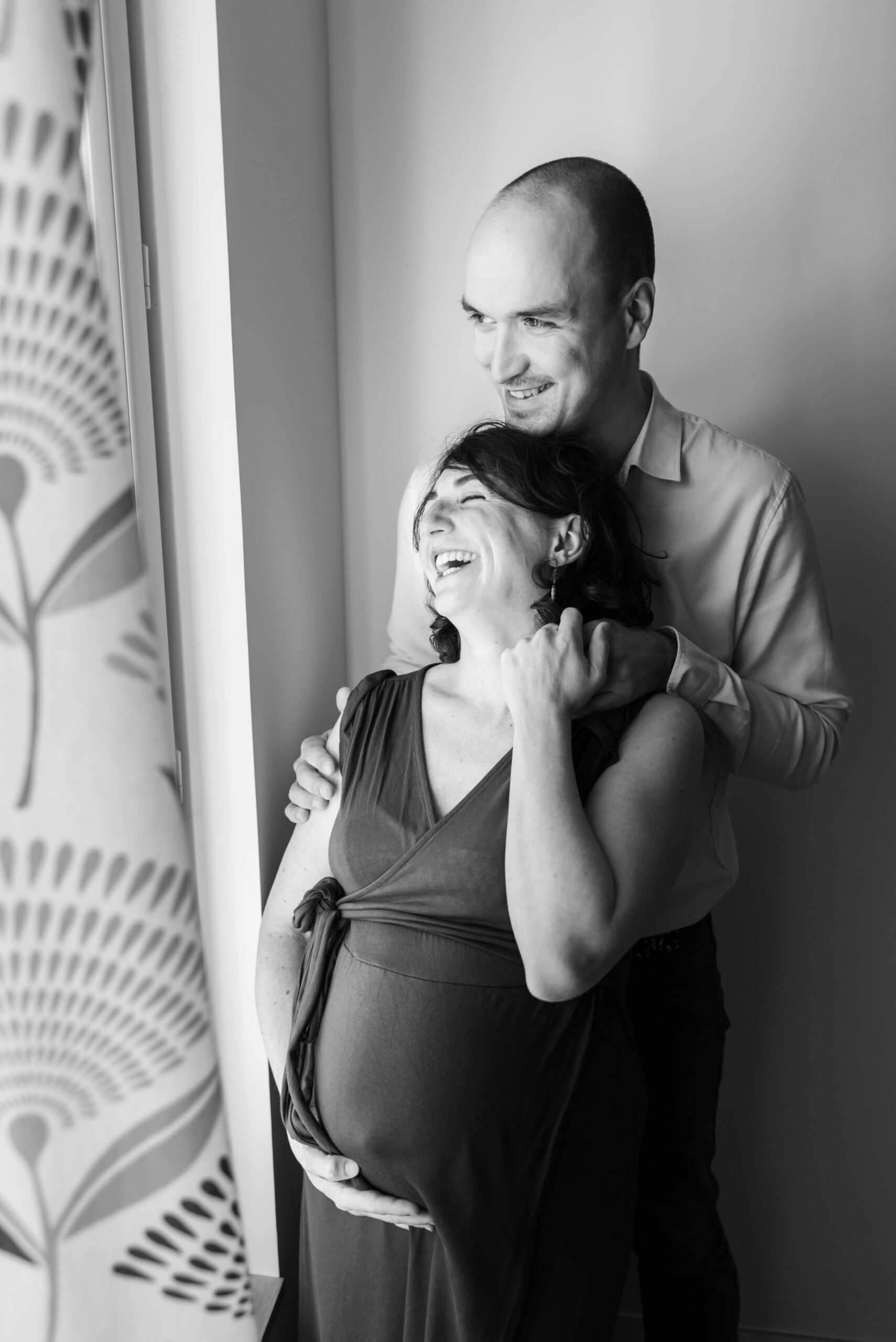 Photographe de grossesse, séance grossesse paris , couple devant une fenêtre