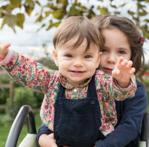 Photographe de famille, sœurs assisses sur un toboggan à Paris