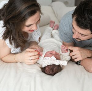 Photographe de naissance, parents et leur bébé, allongés sur leur lit, à Paris